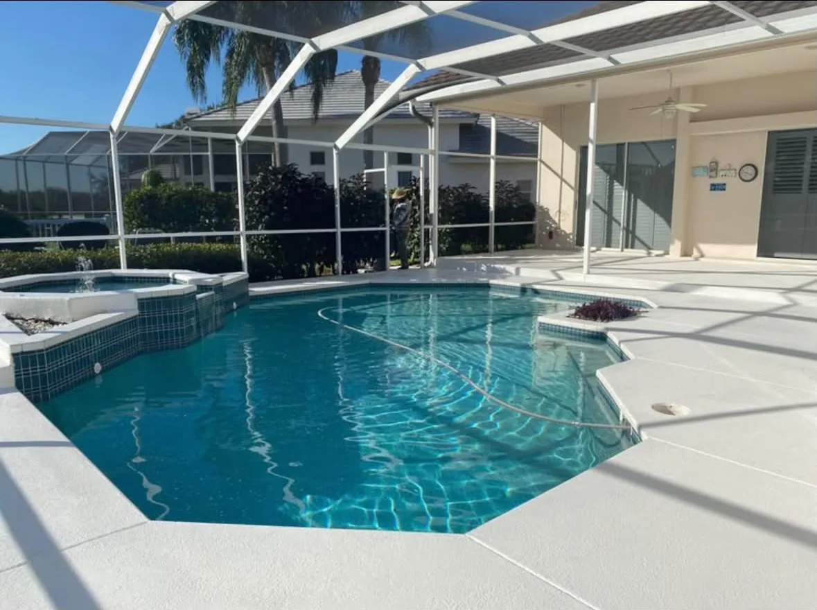 Light textured pool deck surrounding a screened pool and spa